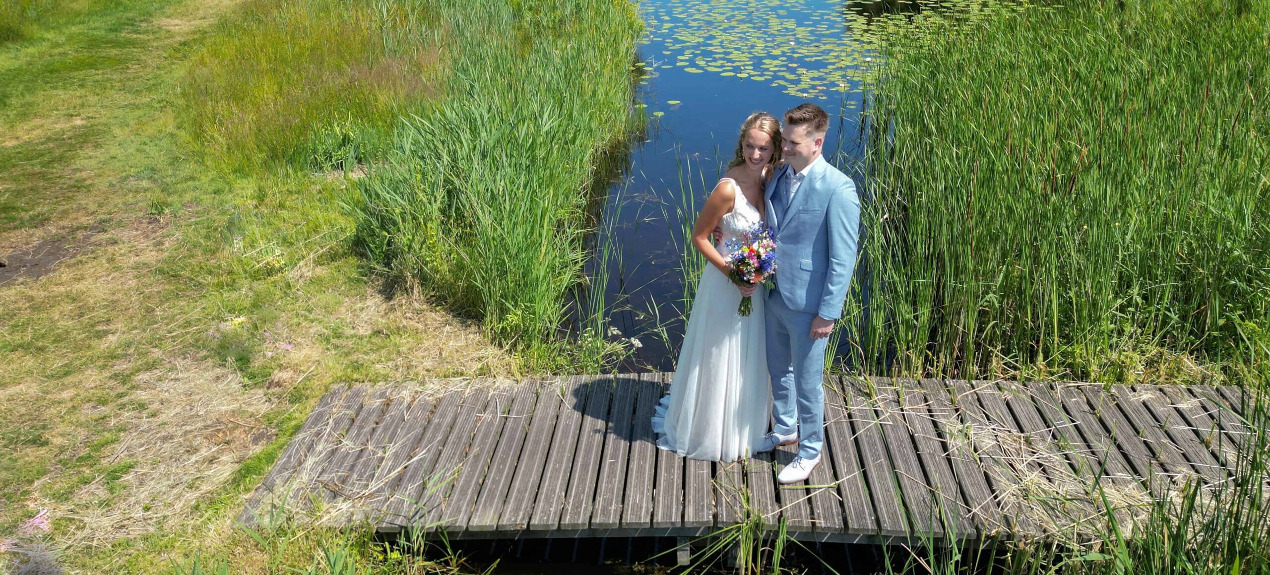 Bruidspaar in natuurgebied op bruggetje. Foto door drone van toruwfotograaf